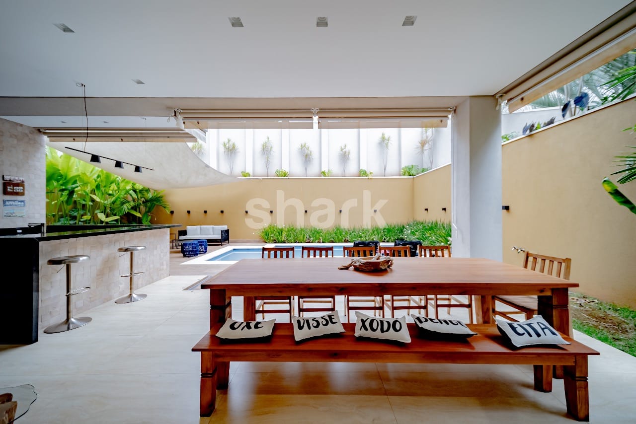 Espaço gourmet com bar, banquetas e mesa de madeira para doze