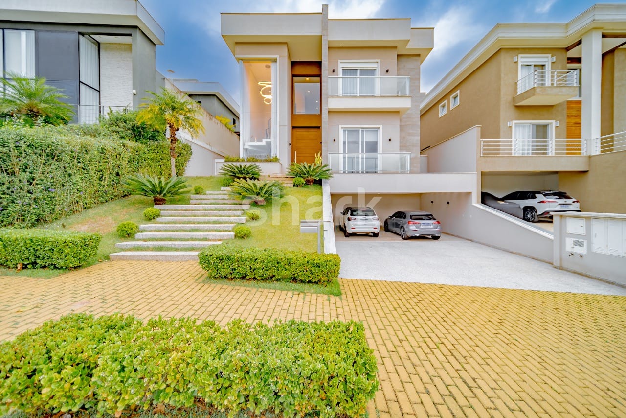 Fachada frontal da casa com escadaria ajardinada e garagem coberta