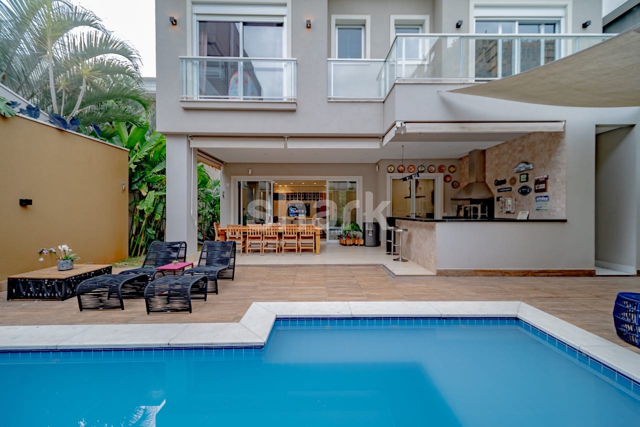 Área da piscina vista de dentro d'água, com espreguiçadeiras e o espaço gourmet